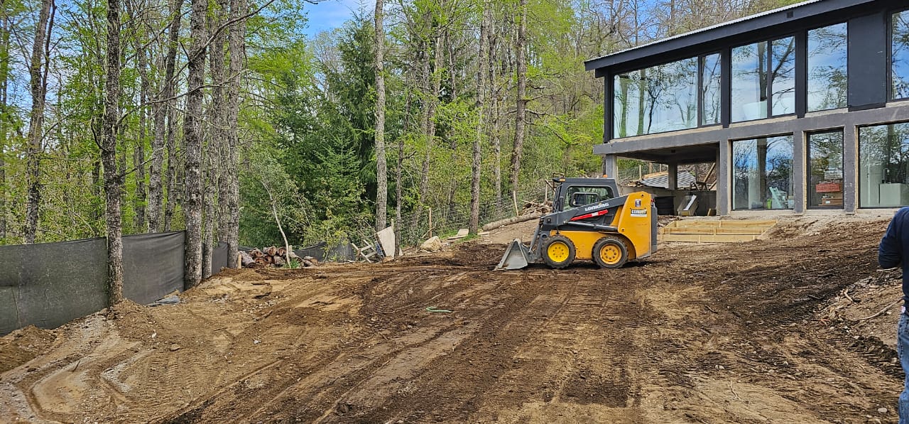 Minicargadora tipo Bobcat de Milenium nivelando el terreno frente a una obra en la cordillera