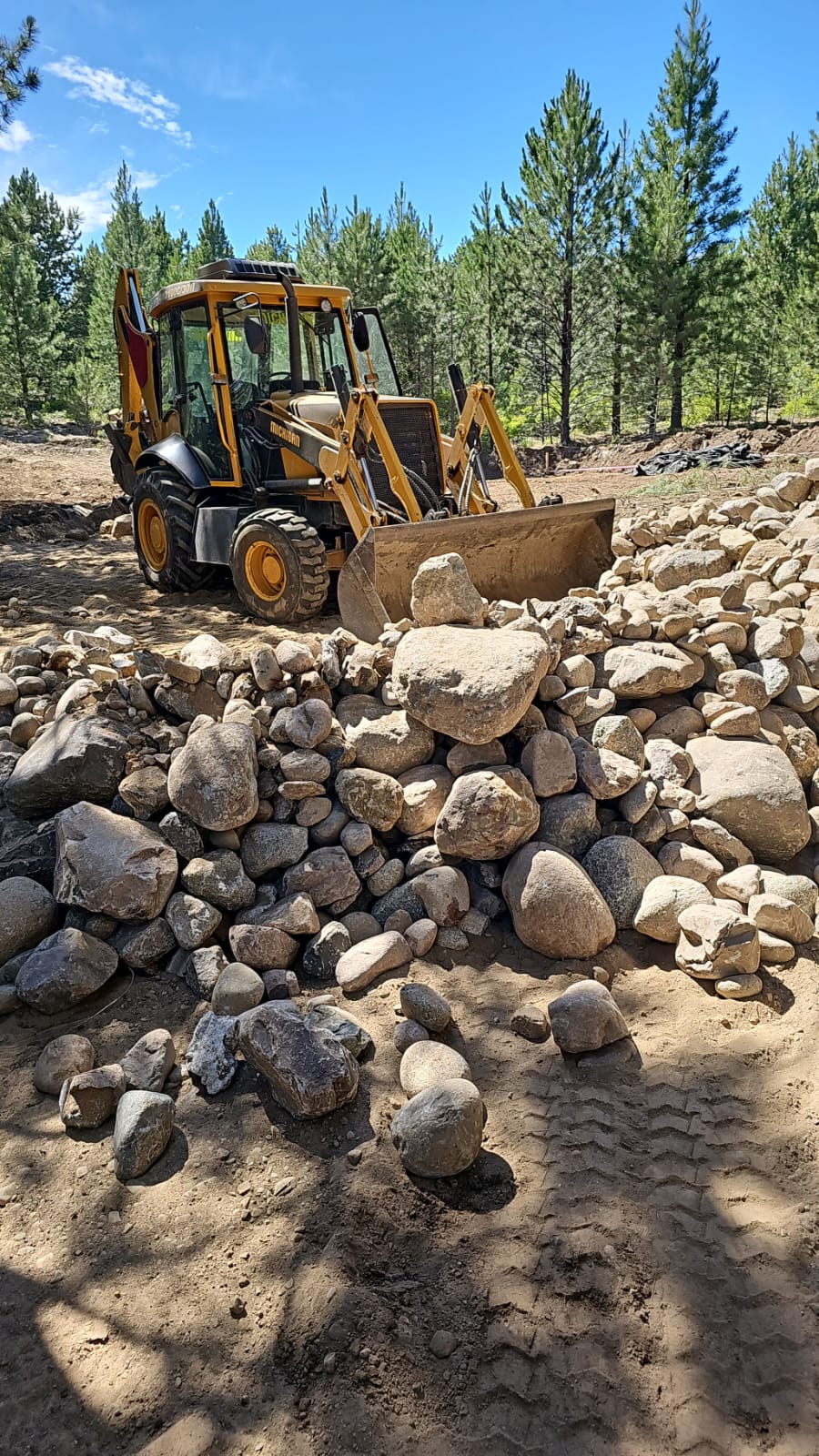 Retropala de Milenium junto a una pila de piedras para venta de áridos